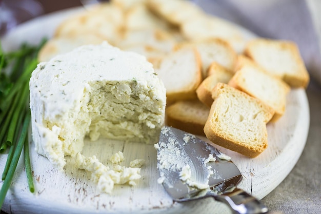 크래커와 함께 나무 판자에 마늘과 고운 허브를 곁들인 부드러운 맛의 크림 치즈.