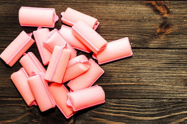 Soft foam comfortable hair curlers on wooden background.