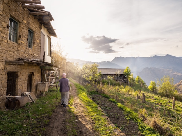 Photo soft focus. authentic rural woman walks through a mountain village. view from the back. dagestan. kakhib.