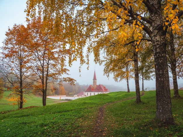 Soft focus. Autumn morning landscape. Bright autumn foggy landscape with golden trees and old Palace. Gatchina. Russia.