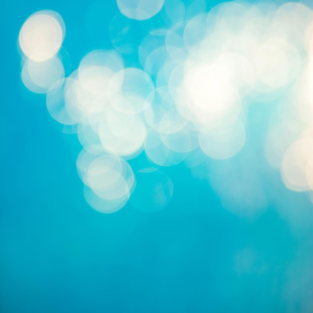 Soft focus bokeh light effects over a rippled blue water background in the pool