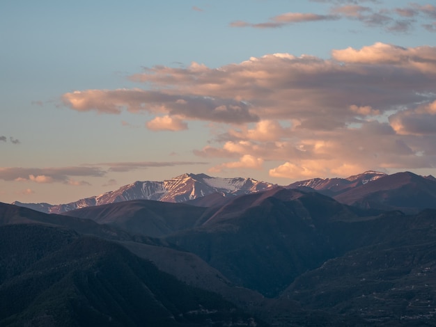 Soft focus. Caucasus mountains at dawn. Atmospheric landscape with silhouettes of mountains on background of pink dawn sky. Colorful nature scenery with sunset or sunrise. Sundown in faded tones.