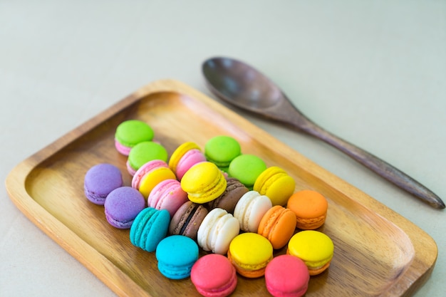 Soft focus of  Colorful Pastel Macarons in wooden dish on table with green wall background