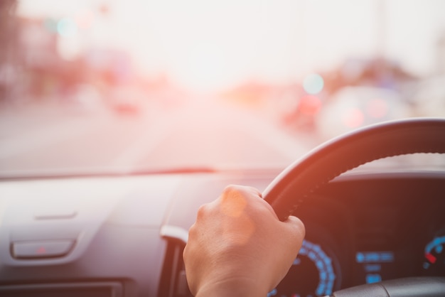 Soft focus driver hand holding steering wheel while driving on the road. 