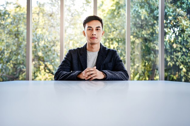 Soft Focus of Happy Young Businessman Sitting at the Table in Office