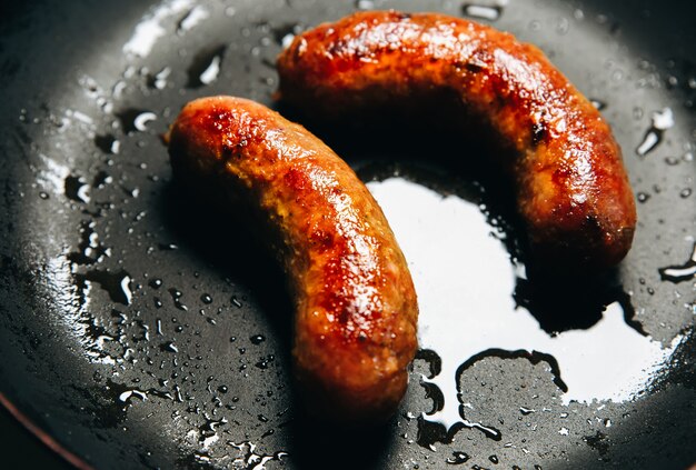 Soft focus photo. Fried sausages on the pan. Unhealthy breakfast. English and German style cuisine.