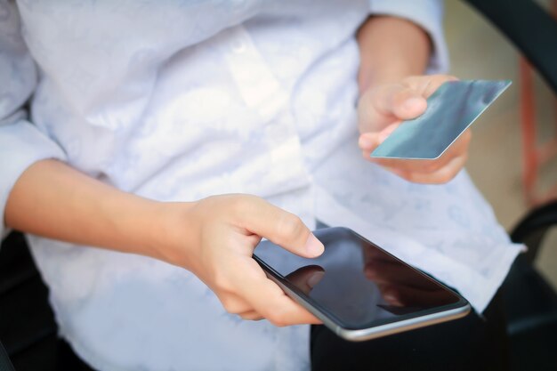 Foto donna asiatica del fuoco molle che usando telefono e carta di credito che compera online, fuoco selettivo a disposizione