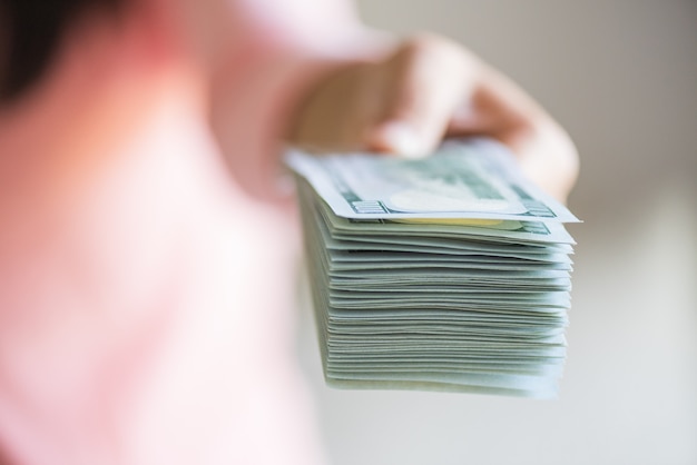 Soft focus on woman hands proposing money us dollar bills to you. 