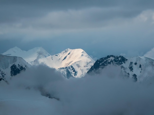 ソフトフォーカス低い雲の上に大きな雪の山の頂上がある素晴らしいミニマリストの風景曇り空に大きな雪の山の頂上がある大気のミニマリズム