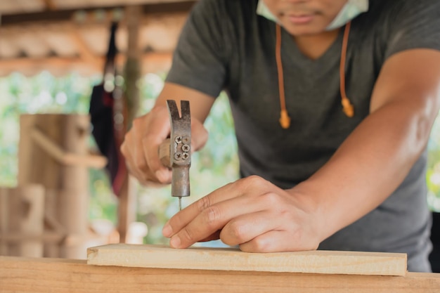 Soft focus wood craftsman using a hammer hammering nails wood\
make product working at carpentry workshop furniture project