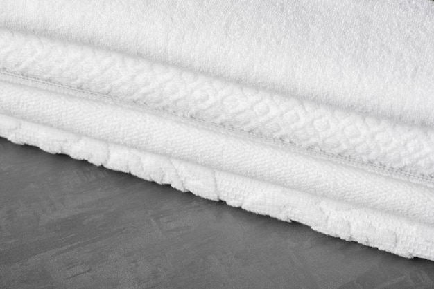 A soft folded bath towel on the gray surface, close-up