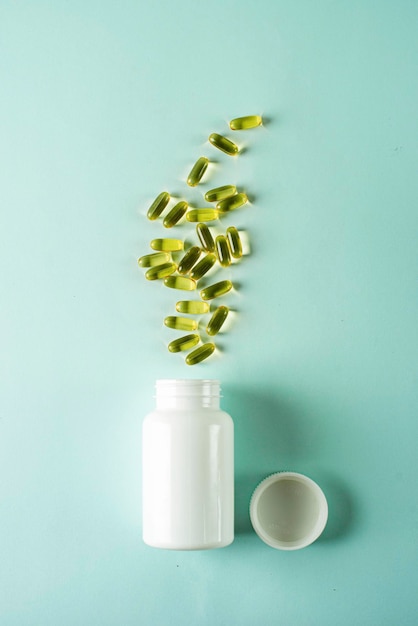 Soft gelatin capsules with fish oil in a white bottle closeup top view