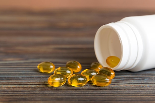 Pillole di gel morbidi con olio omega3 che fuoriesce dal flacone di pillola primo piano capsule di gel flacone superficie bianca multivitaminici omega 3 antibiotici di calcio immunità alla salute