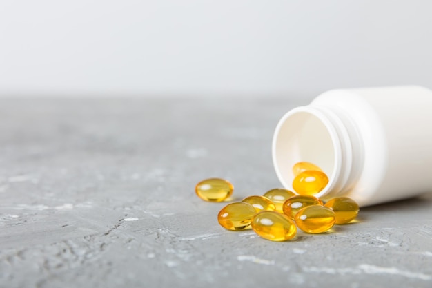 Pillole di gel morbidi con olio omega3 che fuoriesce dal flacone di pillola primo piano capsule di gel flacone superficie bianca multivitaminici omega 3 antibiotici di calcio immunità alla salute