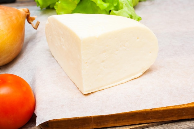 soft goat cheese in a bowl on a wooden table with vegetables