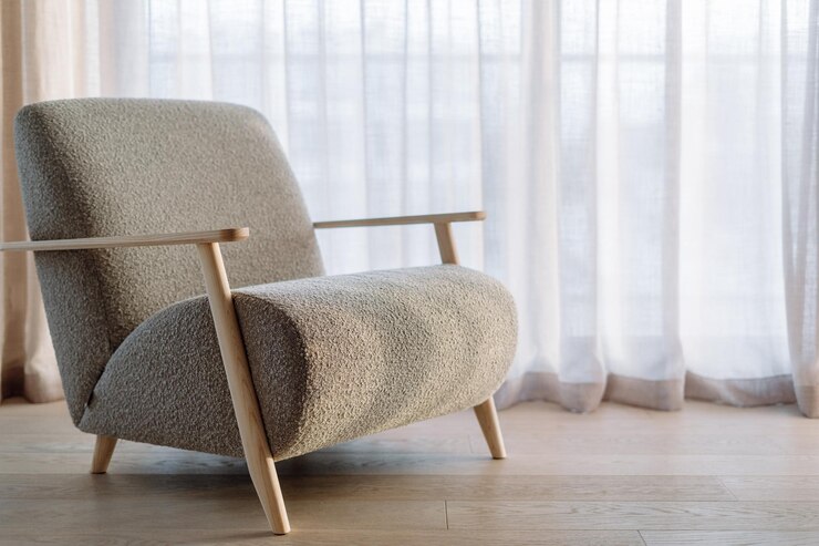 Soft grey armchair against windows with linen curtains