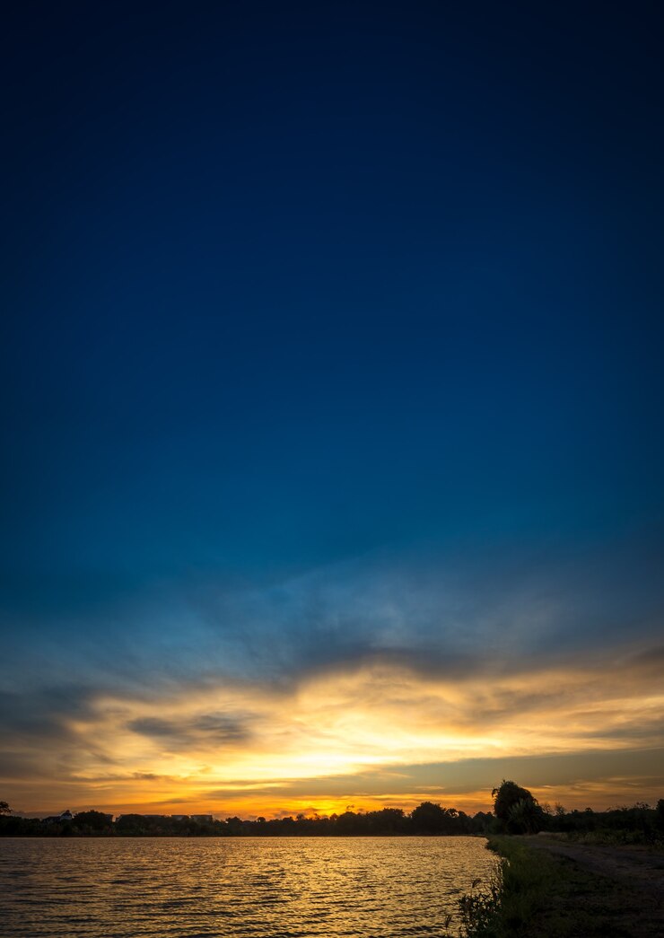 Photo 日没時の川沿いの青い空に柔らかくモーションブラー雲
