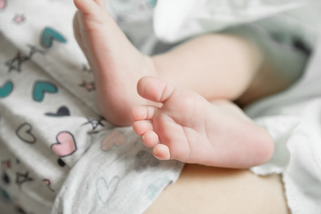 Soft newborn baby feet on mother's hands