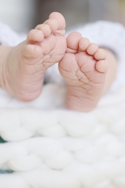 Soft newborn baby feet on the white blanket