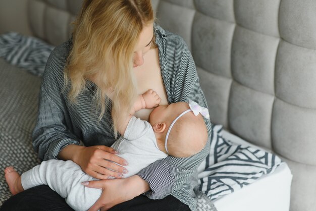 Фото Мягкие фото молодой матери, кормящей грудью своего ребенка дома в белой комнате