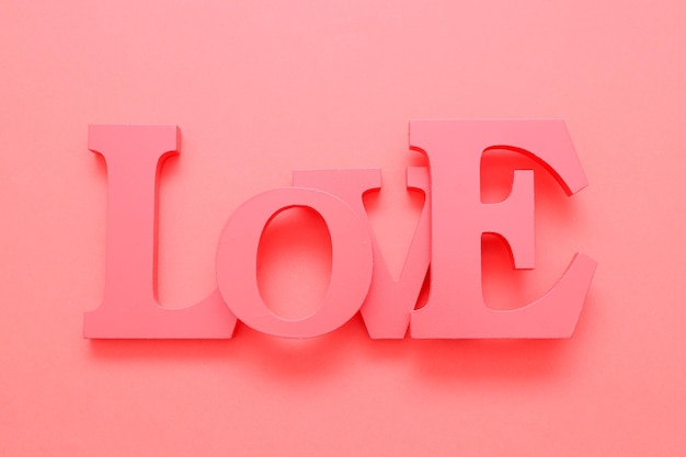 A soft pink word love from wooden letters lies in the center on a soft pink