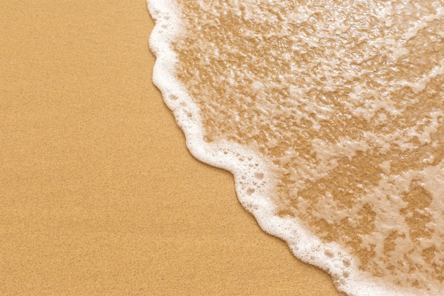 Foto morbida onda del mare sulla sabbia dorata.