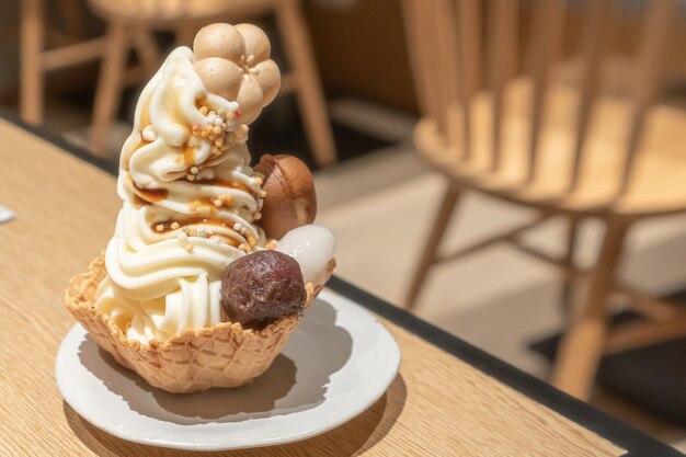 soft-serve or ice cream topping with mochi, mash taro, and some bakery put in a wafer bowl with cafe environment