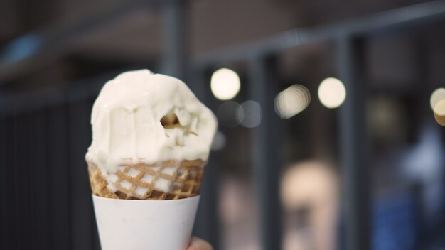 Soft serve ijshoorntje wordt gebeten en smelt in de hand.