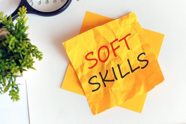 Soft skills schrijven op verfrommeld geel papier, werkplek, brainstormen. Defocussen. Rode letters.