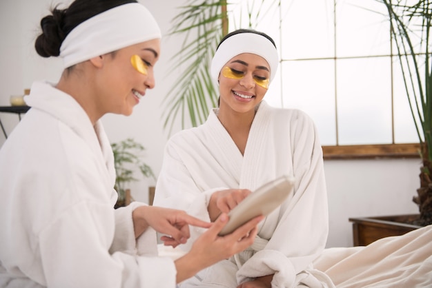 Soft skin. Cheerful young women discussing skin cosmetics while being in the spa salon