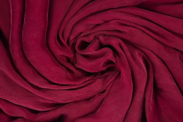 Soft smooth burgundy silk fabric background. Fabric texture.