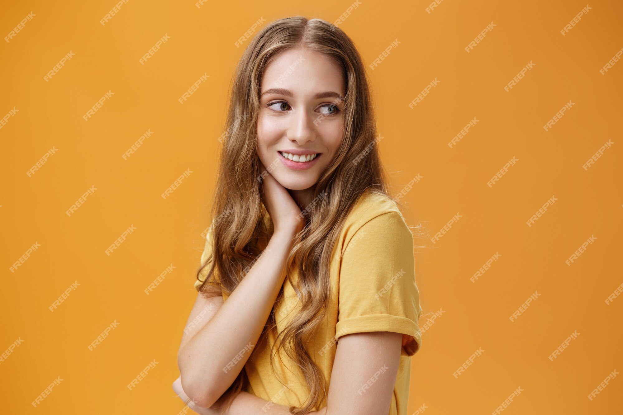 Premium Photo | Soft and tender beautiful young girl with wavy fair hair turning back and look right touching neck gently smiling silly and sincere feeling pretty and self-assured posing over orange Premium Photo | Soft and tender beautiful young girl with wavy fair hair turning back and look right touching neck gently smiling silly and sincere feeling pretty and self-assured posing over orange