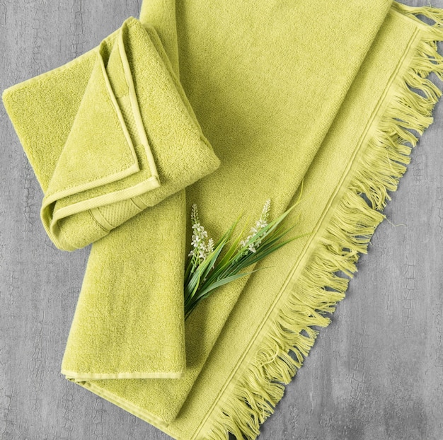 Soft towel with a flower in a grey decorative stucco background top view isolated