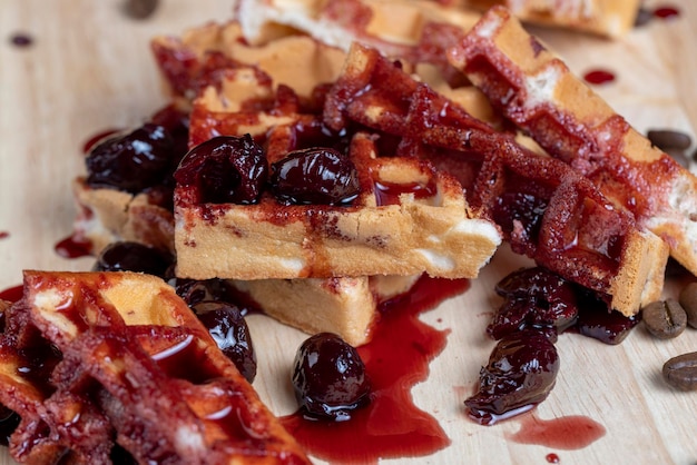 Soft waffles with red cherry jam on a serving board