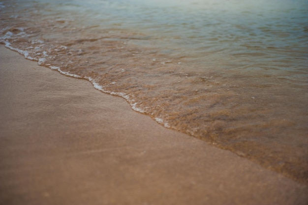 砂浜のビーチの背景に青い海の柔らかい波