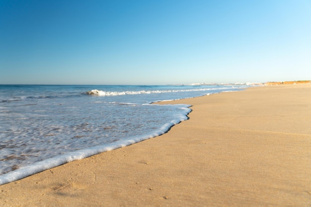 Soft wave on the long sandy beach of Vilamoura in the Algarve in Portugal