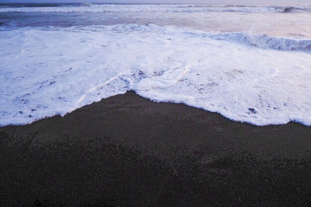 Foto dolce ondata di oceano blu bianco sulla spiaggia di sabbia nera bel paesaggio per lo sfondo