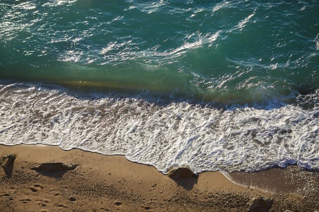모래 해변에 부드러운 파도와 바다 거품. 여름 시즌에 화창한 날에 바다 경치