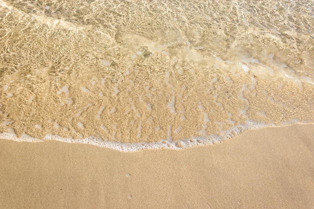 砂浜の背景にある海の泡と柔らかい波
