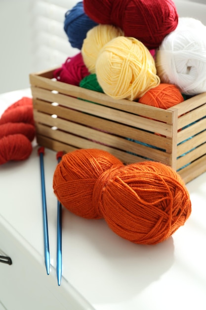 soft yarn in crate and knitting needles on chest of drawers indoors closeup
