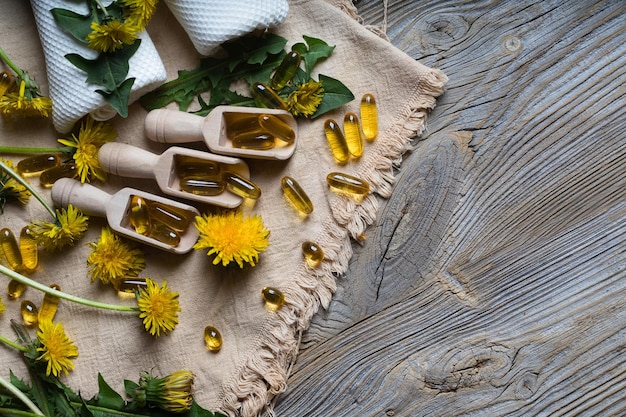 Softgels of dandelion extract on wooden spoons. Closeup