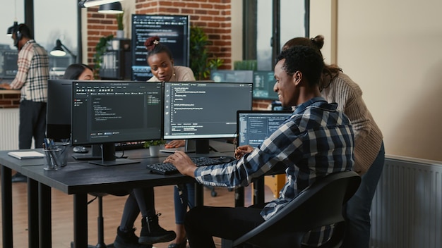 Lo sviluppatore di software che esamina l'esecuzione del codice su più schermi si toglie gli occhiali e fa il gesto della mano con il cinque con il collega programmatore. i programmatori celebrano il successo del cloud computing online.