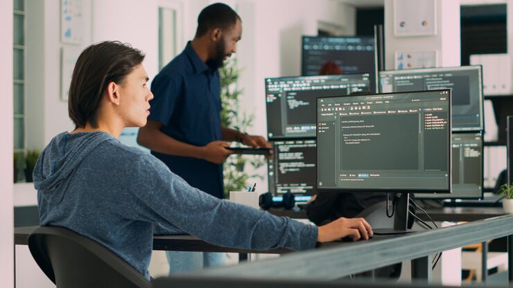 Photo software developer typing learning app code on computer, sitting at desk in big data office. cloud programer working with html database script in cyber security agency. handheld shot.