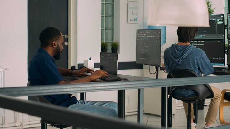 Photo software developer working on temrinal window with html script and writing server code, sitting in data room. system engineer programming user interface in busy developing agency. tripod shot.