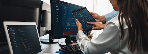 ソフトウェア開発チームは、オフィスのコーディング スクリプトをコンピューターのモニターに表示して一緒に作業しています。技術開発会社 Trailblazing で働くプログラマーとソフトウェア エンジニア