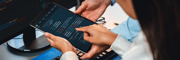 ソフトウェア開発チームは、オフィスのコーディング スクリプトをコンピューターのモニターに表示して一緒に作業しています。技術開発会社 Trailblazing で働くプログラマーとソフトウェア エンジニア