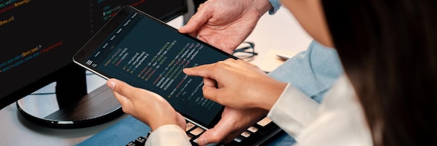 ソフトウェア開発チームは、オフィスのコーディング スクリプトをコンピューターのモニターに表示して一緒に作業しています。技術開発会社 Trailblazing で働くプログラマーとソフトウェア エンジニア