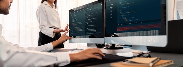 Команда разработчиков программного обеспечения работает вместе в офисе, отображая сценарий кодирования на мониторе компьютера. Программист и инженер-программист, работающий в компании-разработчике технологий Trailblazing
