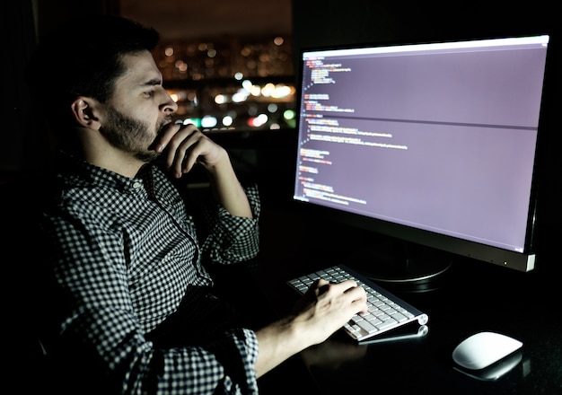 Softwareontwikkelaarcomputer op donker kantoor aan huis