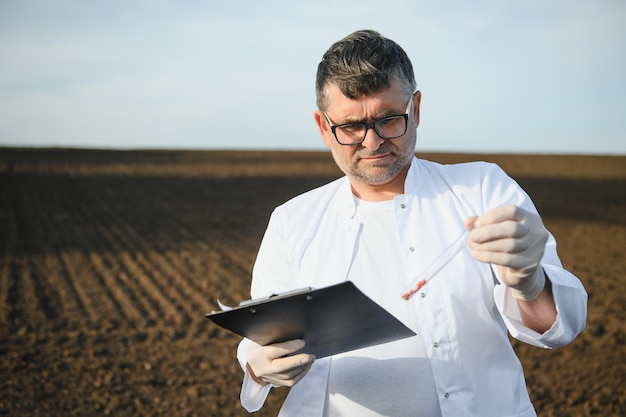 Foto campionamento del suolo agronomo che preleva il campione con il campionatore della sonda del suolo ricerca di certificazione del suolo organico per la protezione dell'ambiente